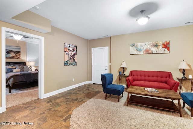 living room featuring ceiling fan, visible vents, baseboards, and stone finish floor