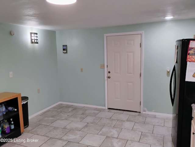 interior space featuring baseboards and freestanding refrigerator