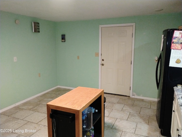 kitchen featuring white cabinets, baseboards, freestanding refrigerator, and light tile patterned floors
