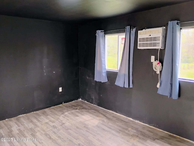 unfurnished room featuring wood finished floors and an AC wall unit