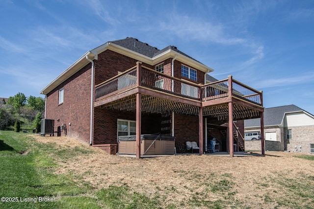 rear view of house with brick siding, cooling unit, a hot tub, and a deck