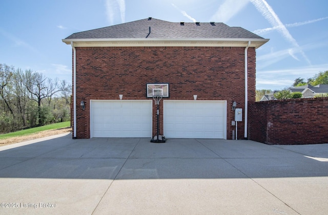 view of side of home featuring brick siding, driveway, roof with shingles, and a garage