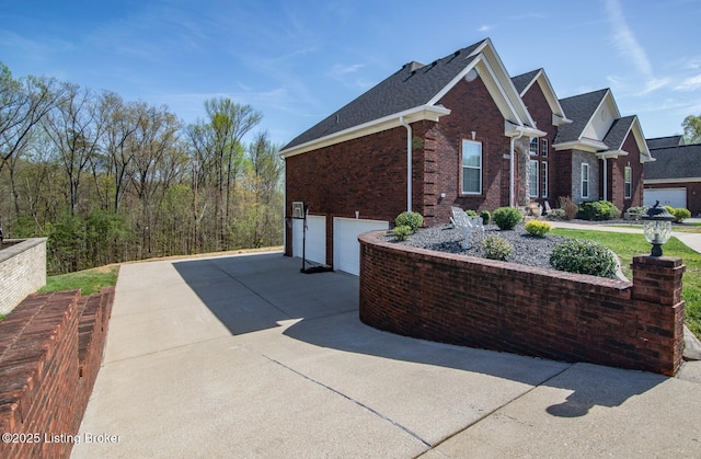 view of home's exterior with an attached garage, driveway, and brick siding