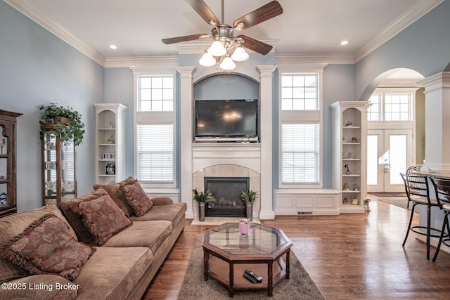 living room with a ceiling fan, wood finished floors, arched walkways, a tile fireplace, and recessed lighting