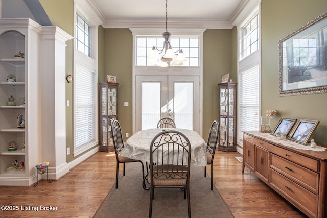 dining room with light wood finished floors, baseboards, ornamental molding, and an inviting chandelier