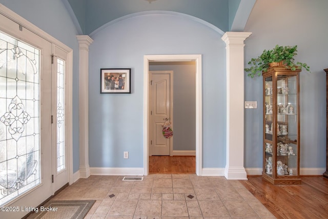 foyer with baseboards, visible vents, arched walkways, and ornate columns