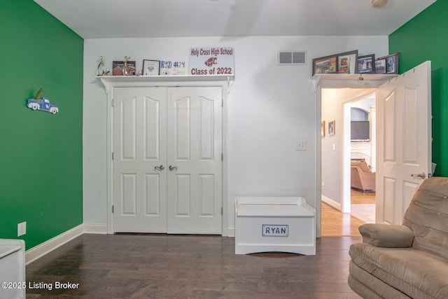bedroom with baseboards, wood finished floors, visible vents, and a closet