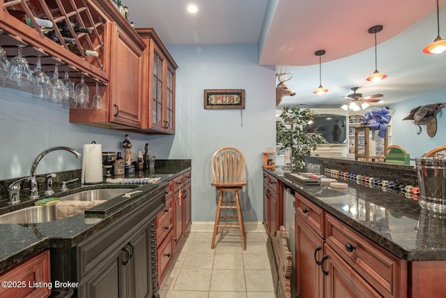 kitchen featuring ceiling fan, pendant lighting, a sink, and glass insert cabinets