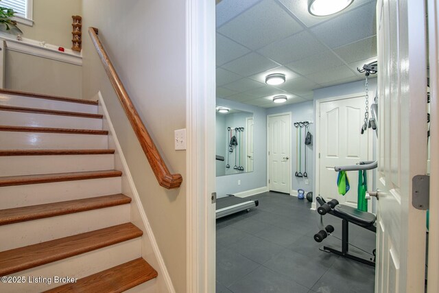 workout room with a drop ceiling and baseboards