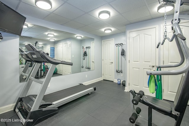exercise room with a paneled ceiling and baseboards