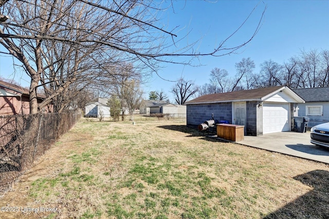 view of yard featuring fence, driveway, an outdoor structure, and a garage