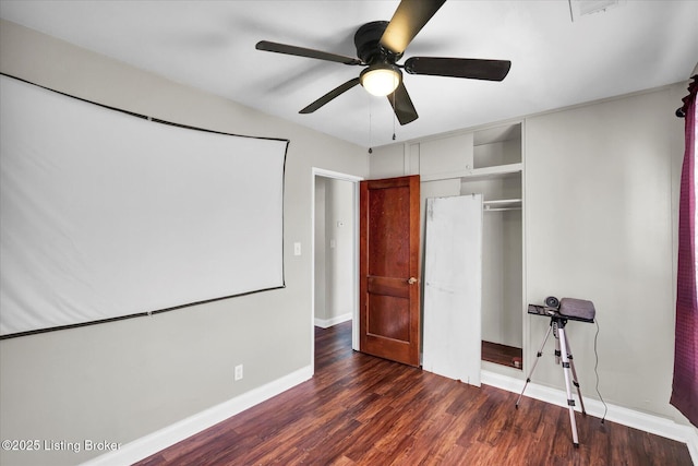 cinema room with ceiling fan, baseboards, and wood finished floors