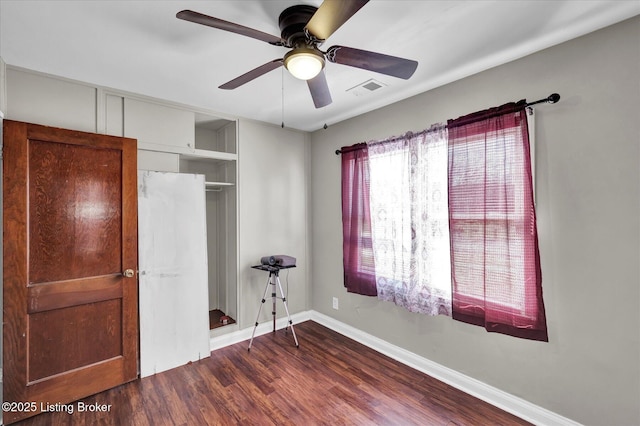 bedroom with wood finished floors, visible vents, a ceiling fan, a closet, and baseboards
