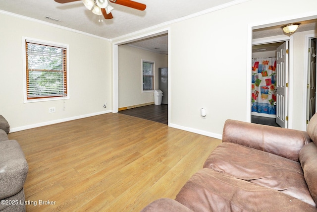 living area with crown molding, ceiling fan, visible vents, and wood finished floors