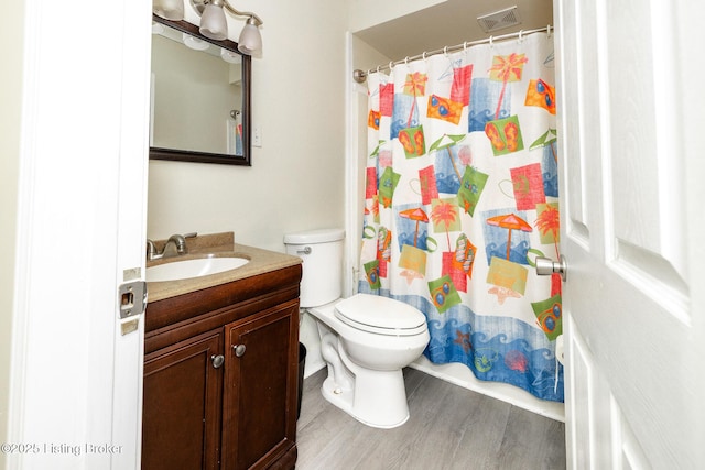 bathroom with a shower with curtain, visible vents, wood finished floors, vanity, and toilet