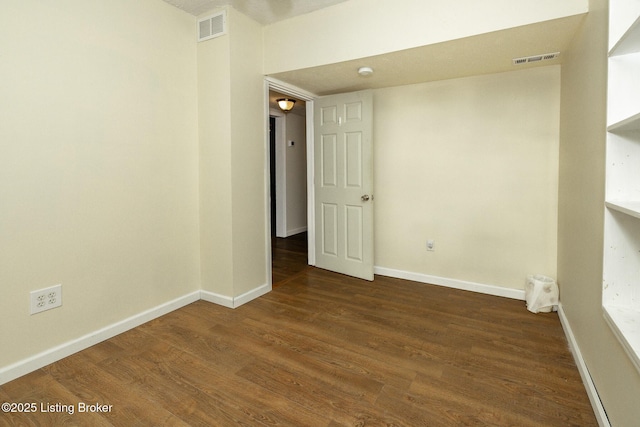 spare room with baseboards, wood finished floors, and visible vents