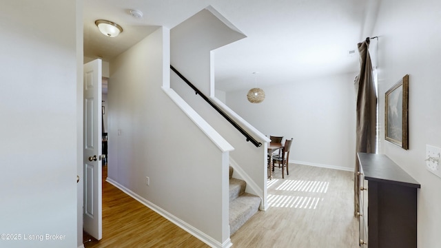 stairway with wood finished floors and baseboards