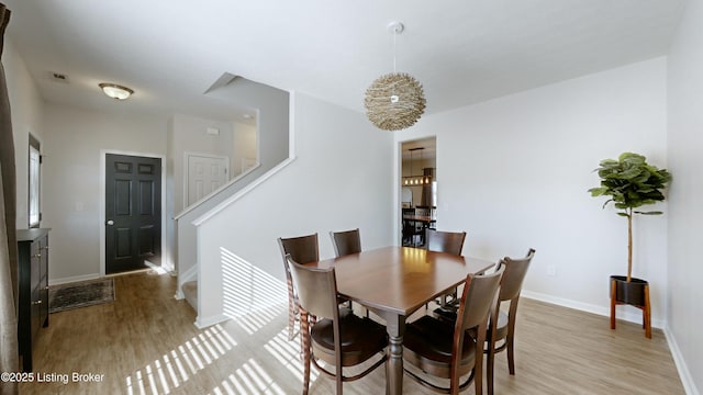 dining room featuring light wood-style flooring, visible vents, baseboards, and stairway