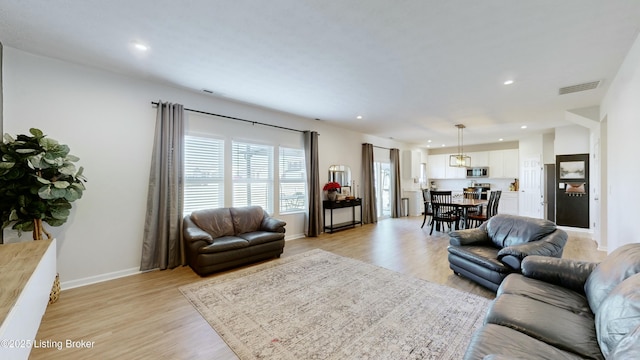 living room with light wood finished floors, visible vents, and recessed lighting