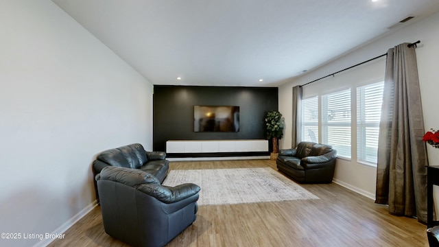 living room featuring visible vents, baseboards, wood finished floors, and a wealth of natural light