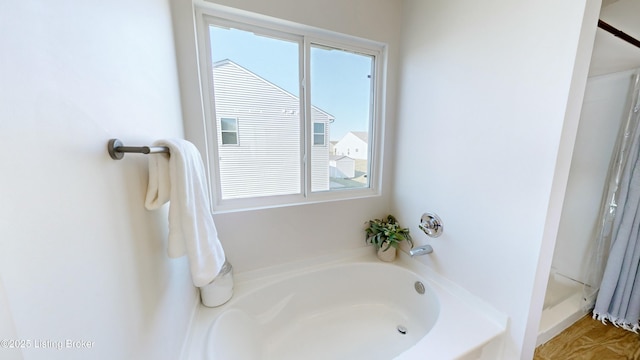 bathroom featuring a shower stall, a garden tub, and a healthy amount of sunlight