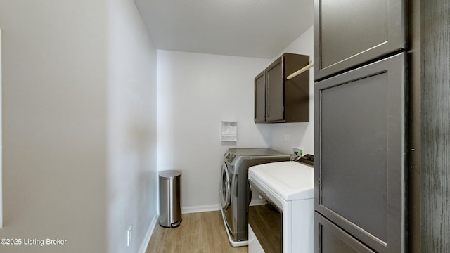 laundry area featuring baseboards, washer and dryer, light wood-style floors, and cabinet space