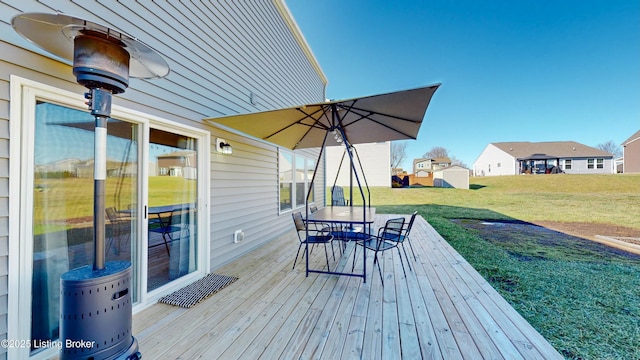 wooden deck featuring outdoor dining space and a lawn