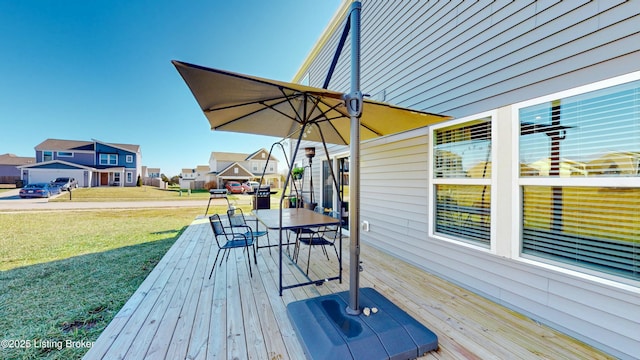 deck featuring a residential view, outdoor dining space, and a lawn
