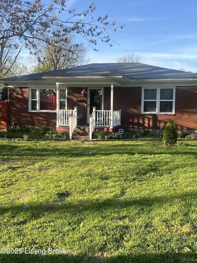 rear view of property featuring a lawn, brick siding, and a porch
