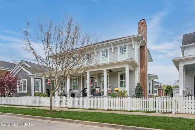 view of front of house featuring a ceiling fan, a porch, a chimney, and a fenced front yard