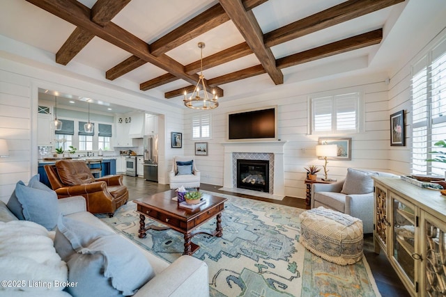 living area with coffered ceiling, an inviting chandelier, and plenty of natural light