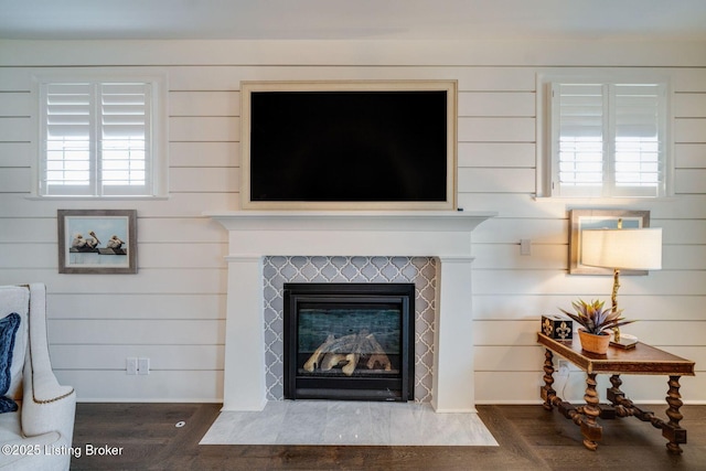 interior details with wood walls, wood finished floors, and a tile fireplace