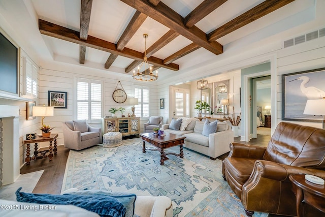 living area featuring an inviting chandelier, wood finished floors, visible vents, beamed ceiling, and a fireplace