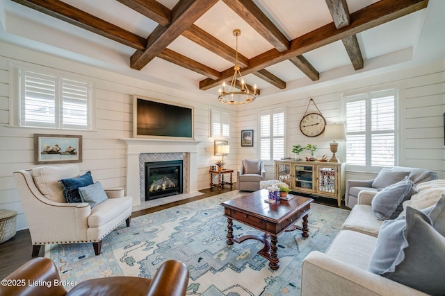 living area with a fireplace with flush hearth, plenty of natural light, an inviting chandelier, coffered ceiling, and wood finished floors