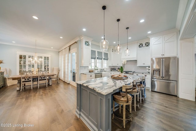 kitchen with stainless steel appliances, tasteful backsplash, a notable chandelier, glass insert cabinets, and light stone countertops