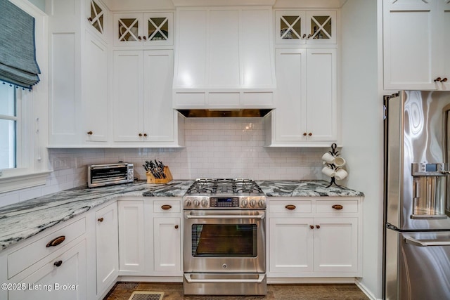 kitchen featuring backsplash, light stone countertops, white cabinetry, and stainless steel appliances