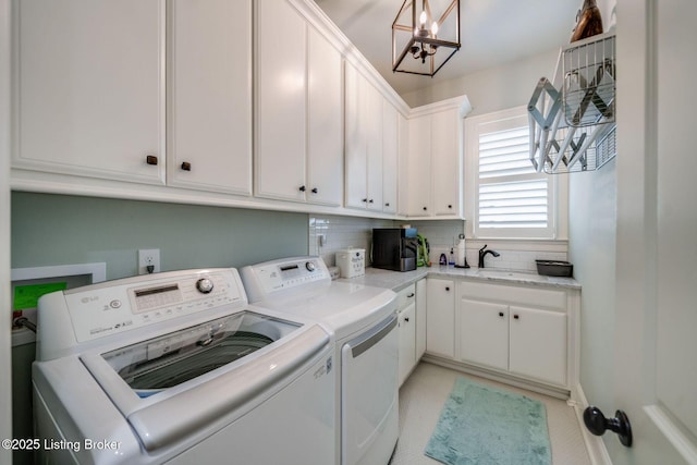 washroom with washing machine and clothes dryer, a sink, a notable chandelier, and cabinet space