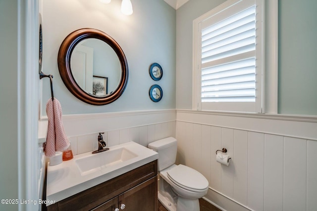 bathroom featuring toilet, vanity, and wainscoting