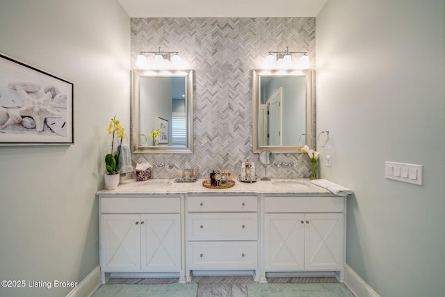full bathroom with baseboards, a sink, backsplash, and double vanity