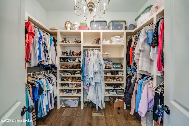 spacious closet with wood finished floors and a notable chandelier