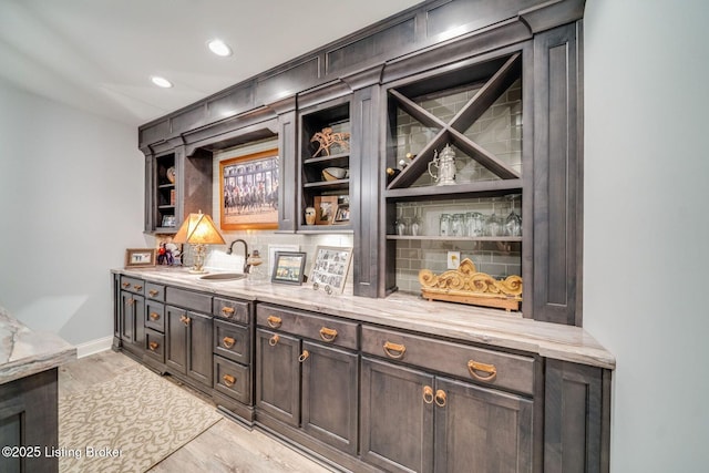 bar with recessed lighting, a sink, light wood-type flooring, baseboards, and tasteful backsplash