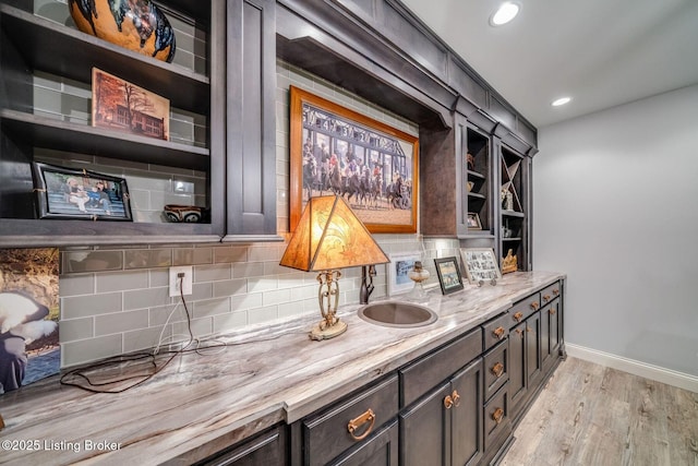 bar featuring recessed lighting, light wood finished floors, a sink, baseboards, and tasteful backsplash