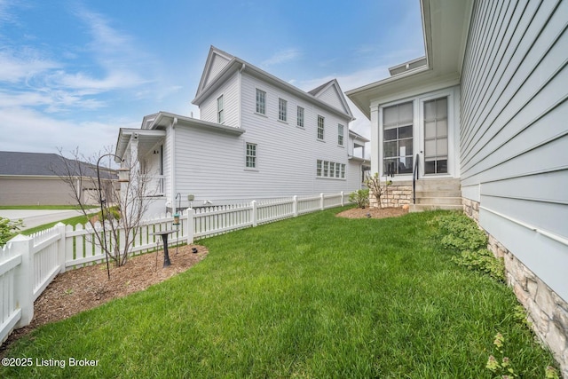 view of property exterior with a yard, entry steps, and fence