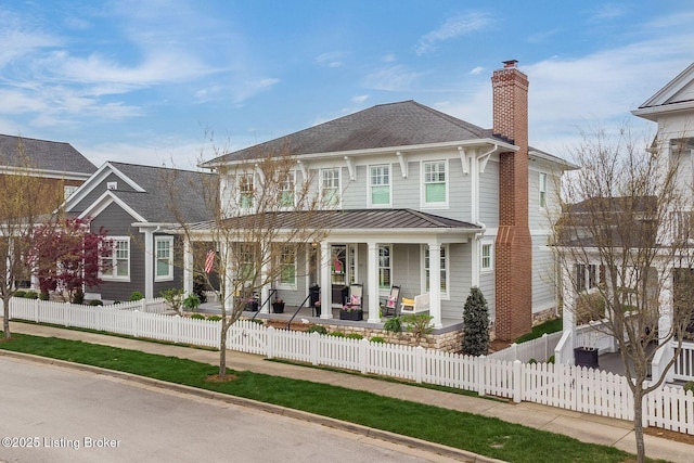 view of front of property featuring a fenced front yard, a chimney, covered porch, metal roof, and a standing seam roof