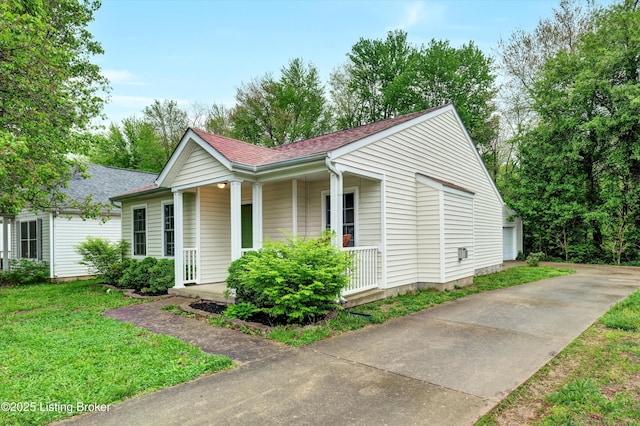view of side of property with a yard, a shingled roof, and covered porch