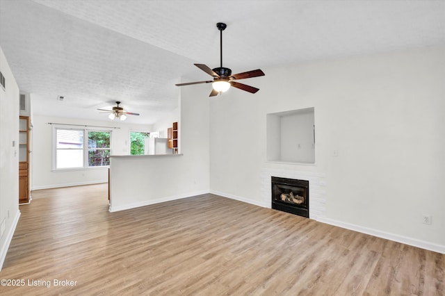 unfurnished living room with lofted ceiling, a ceiling fan, wood finished floors, and baseboards