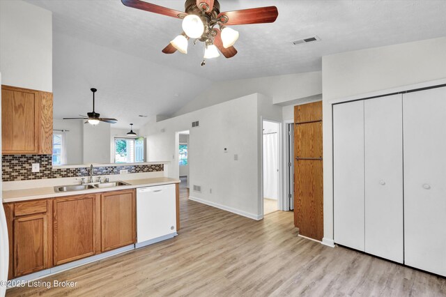 kitchen with a peninsula, a sink, vaulted ceiling, ceiling fan, and dishwasher