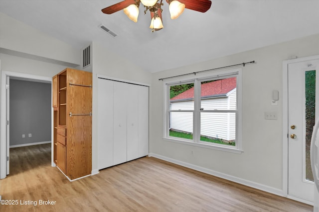 unfurnished bedroom featuring vaulted ceiling, visible vents, a closet, baseboards, and light wood-style flooring