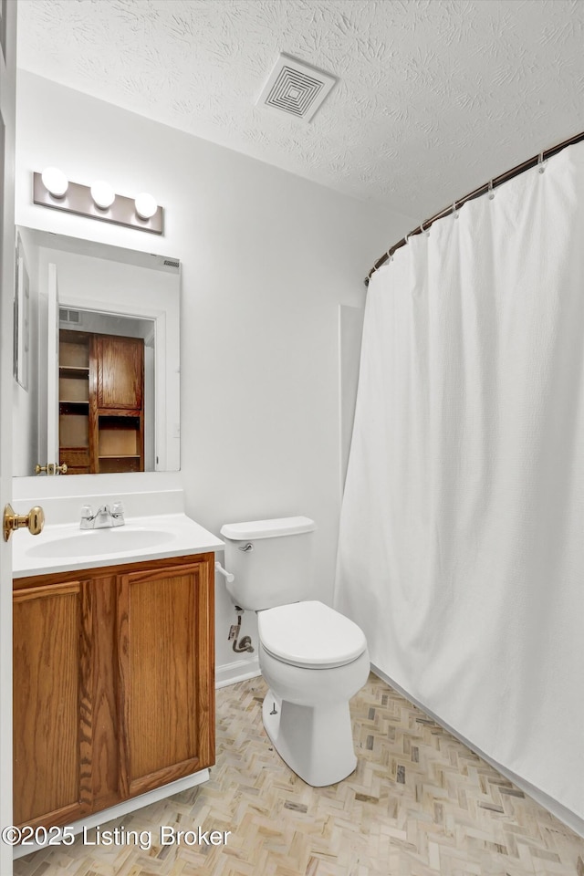 full bathroom featuring a textured ceiling, vanity, a shower with curtain, toilet, and visible vents