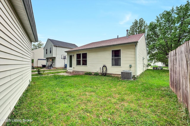 rear view of property featuring central AC and a yard